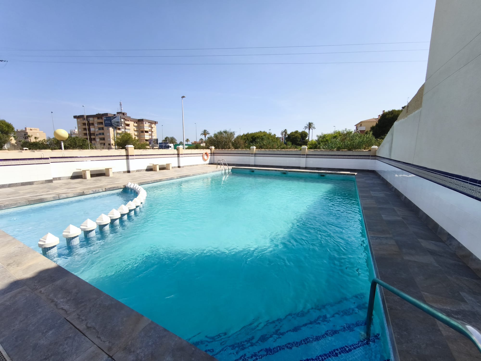 Full community pool with separate shallow section, surrounding deck, and Mediterranean neighborhood views