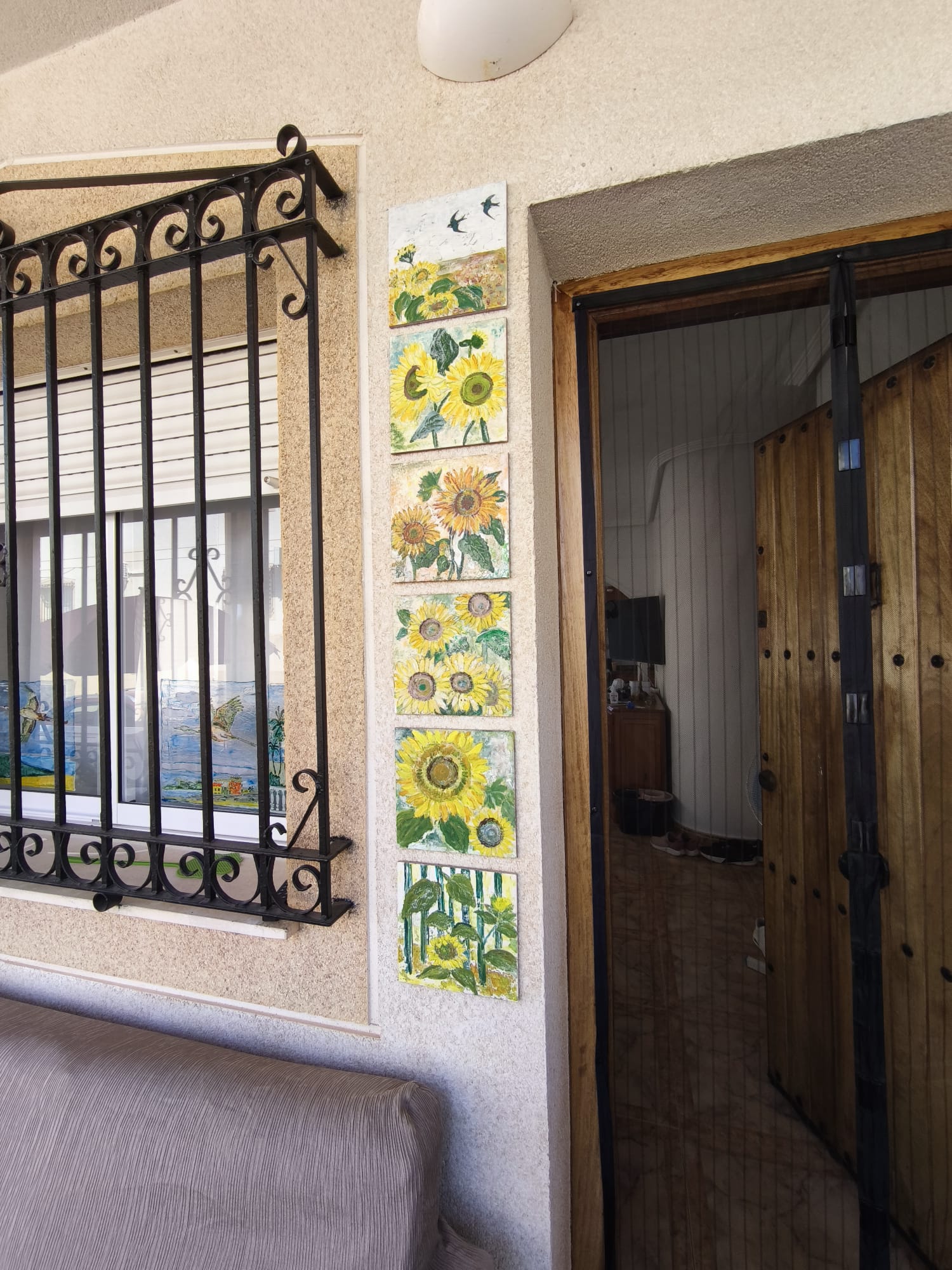 Front entrance with decorative sunflower tile panel, wrought-iron window grille, and wooden front door