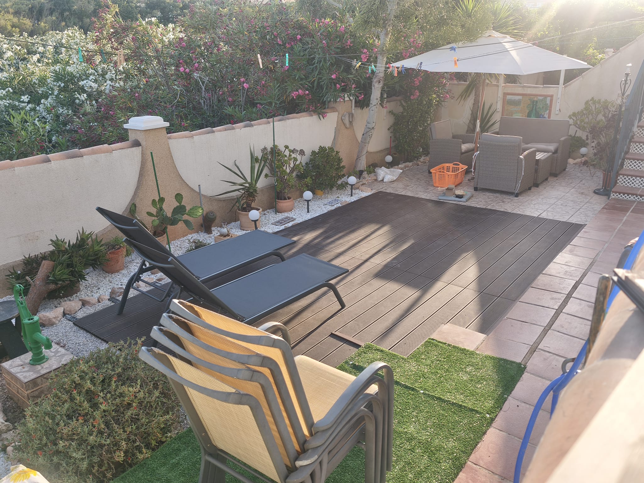 Spacious terrace from above with sun loungers, composite decking, rattan lounge set, parasol, and surrounding Mediterranean plants